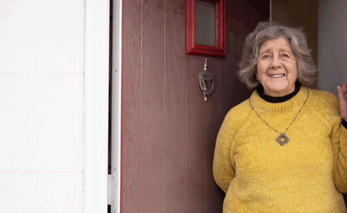 Roedd menyw mewn siwmper felen yn sefyll ym mhorthladd y drws ffrynt.