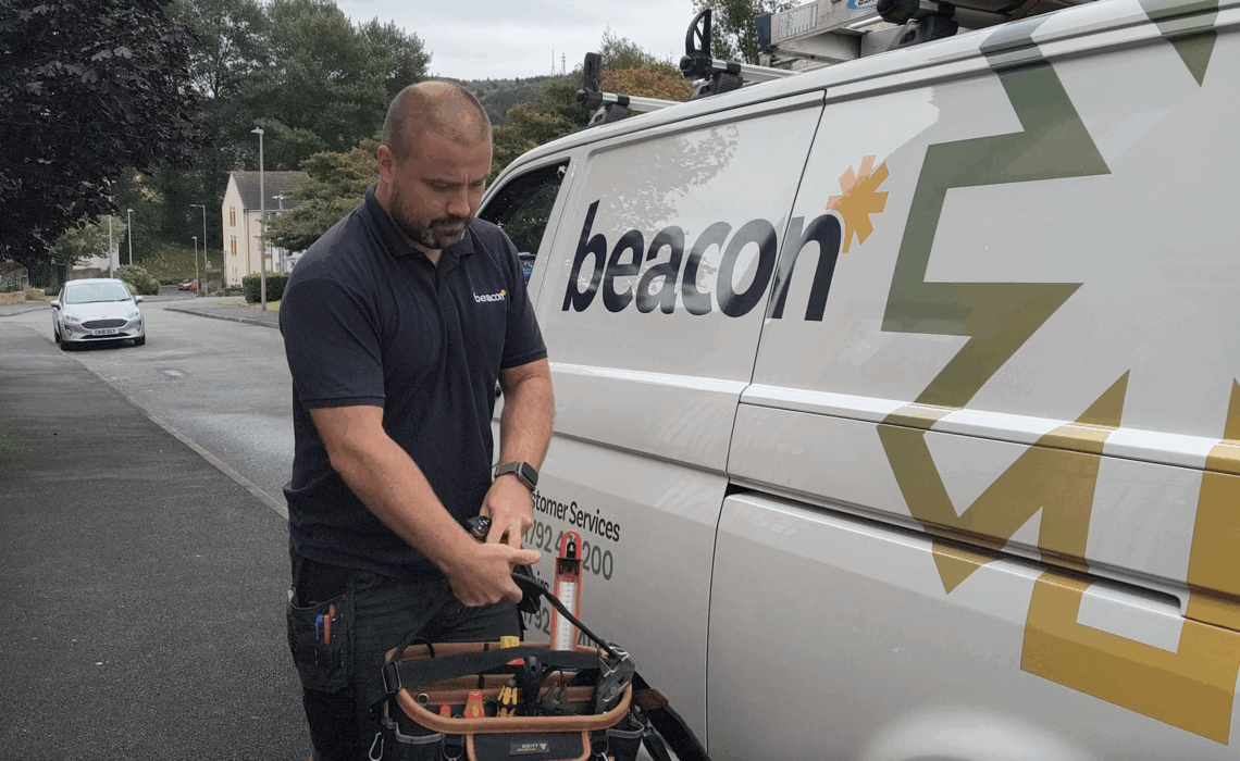 Beacon engineer holding a tool kit walking away from a Beacon van