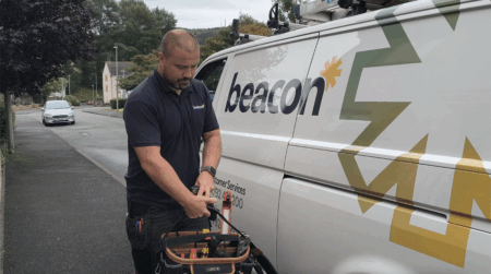 Beacon engineer holding a tool kit walking away from a Beacon van