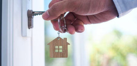 Person holding a key inside a door lock with a house keyring attached
