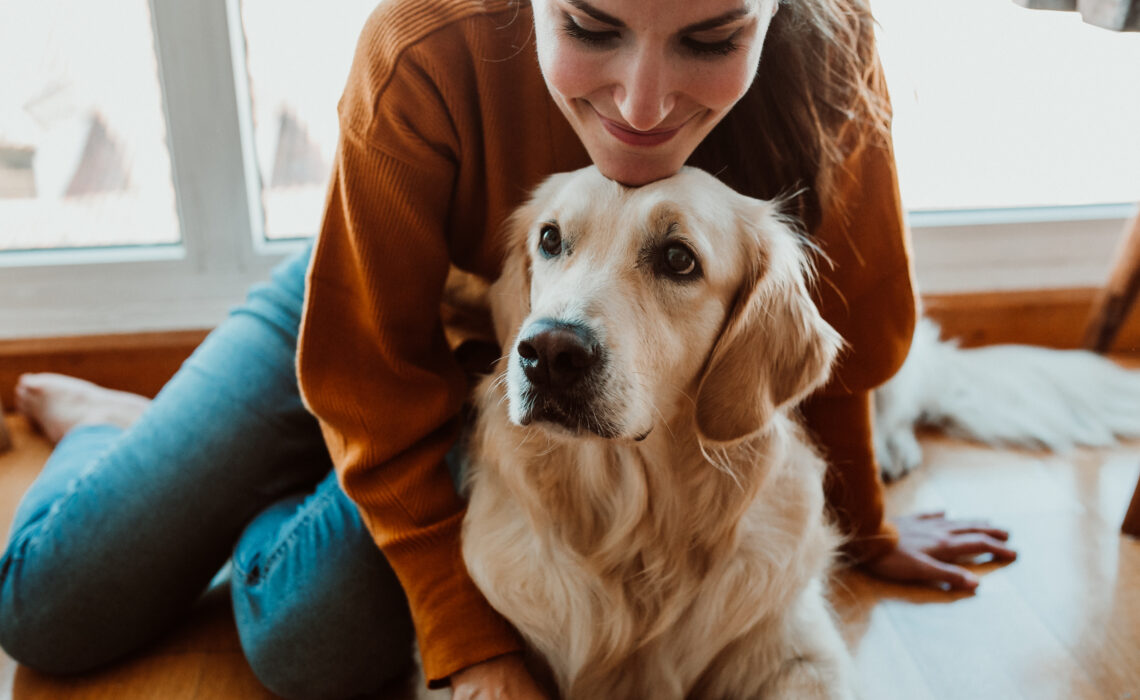 Young woman leaning over a dog in the home
