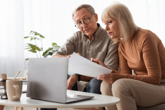 Mature Spouses Reading Papers And Documents Holding Letters At Home