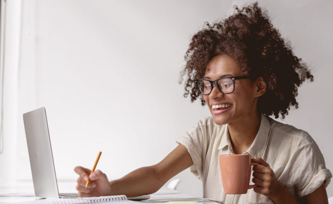 Joyful Young Woman In Glasses Writing Down Notes